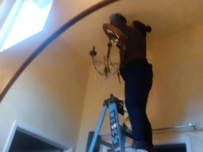 Electrician installing a chandelier in a Clarkson residence